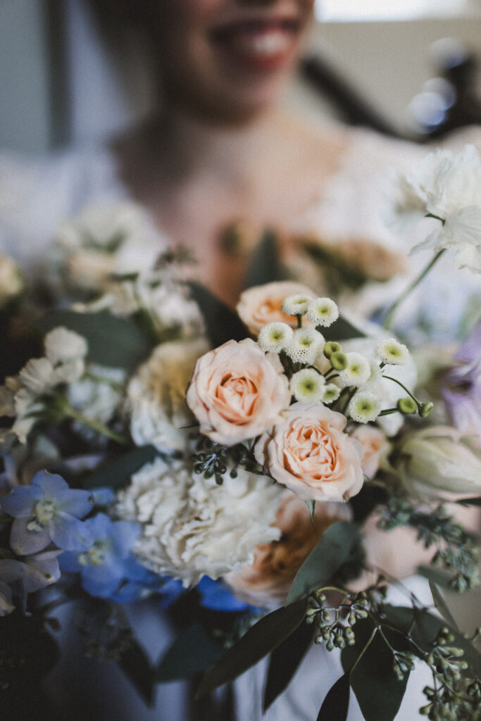 Bride is holding a nice flower bouquet in pastel colours